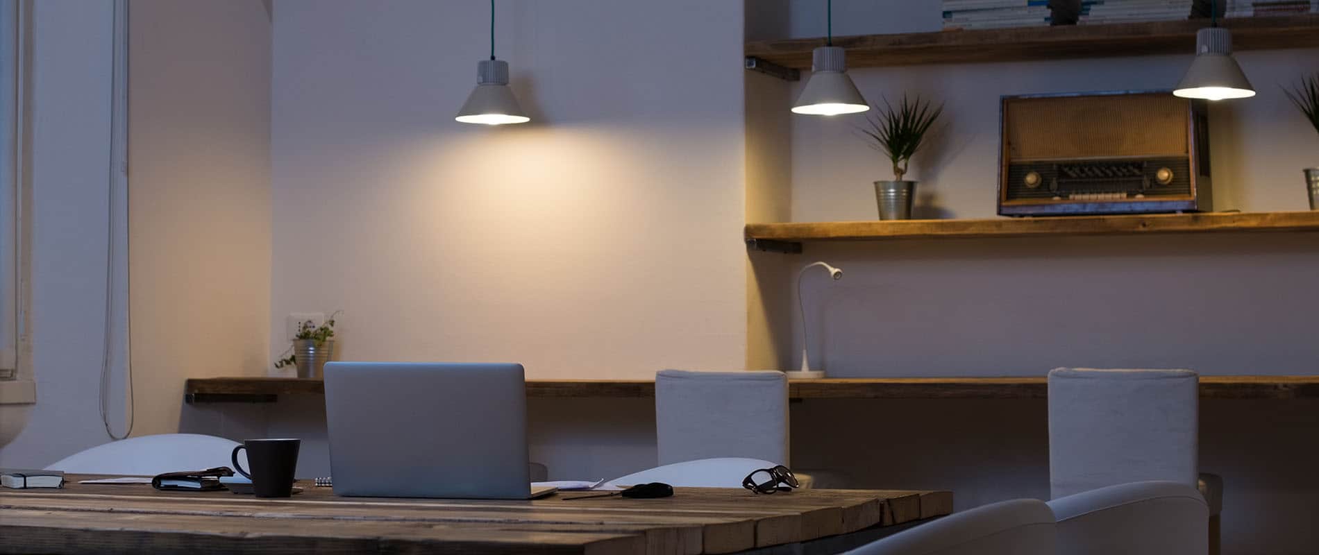 Laptop on desk with empty chairs in modern office